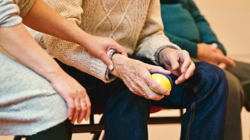 Elderly man holding hands with carer